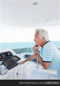 Middle-aged man sitting at helm of yacht side view