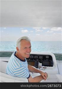 Middle-aged man sitting at helm of yacht smiling