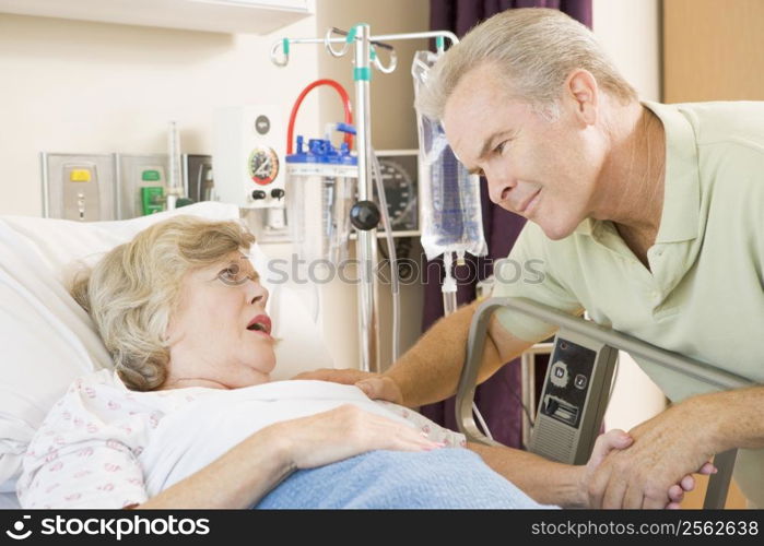 Middle Aged Man Talking To Senior Woman In Hospital