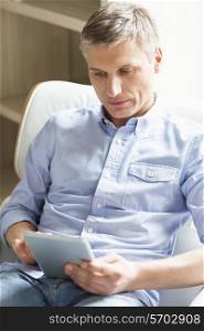 Middle-aged man using digital tablet at home