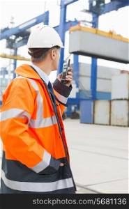 Middle-aged man using walkie-talkie in shipping yard