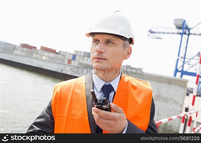 Middle-aged man using walkie-talkie in shipping yard