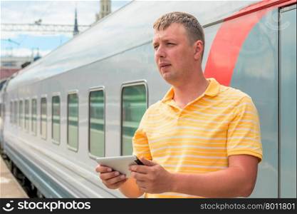 middle-aged man with a tablet beside the train