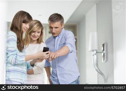 Middle-aged man with daughters using smart phone at home
