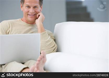 Middle-aged man with laptop on sofa