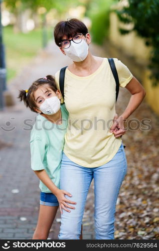 Middle-aged mother and daughter standing on the street wearing masks because of the Covid-19 pandemic. Middle-aged mother and daughter standing on the street wearing masks