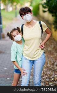Middle-aged mother and daughter standing on the street wearing masks because of the Covid-19 pandemic. Middle-aged mother and daughter standing on the street wearing masks