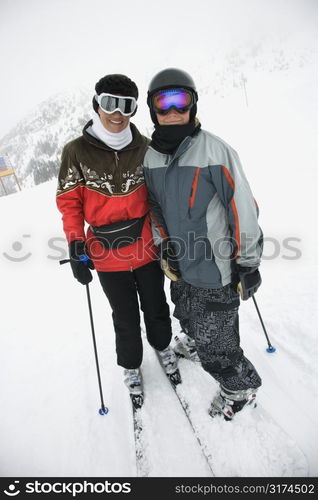 Middle-aged mother with teenage son on snowy ski slopes.