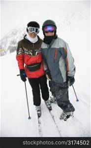 Middle-aged mother with teenage son on snowy ski slopes.