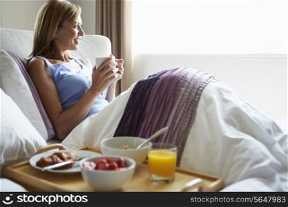 Middle Aged Relaxing In Bed With Hot Drink And Breakfast