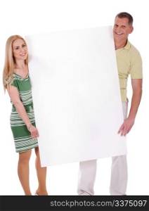 Middle aged smiling couple holding a blank white board over isolated white background