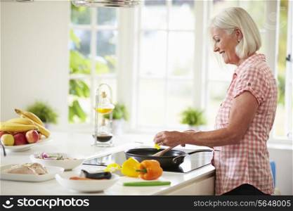 Middle Aged Woman Cooking Meal In Kitchen