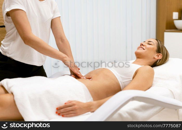 Middle-aged woman having a belly massage in a beauty salon. Body care treatment in a beauty centre.. Middle-aged woman having a belly massage in a beauty salon.