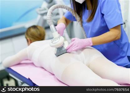Middle-aged woman in special white suit having a anti cellulite massage with spa apparatus. Woman in special white suit having a anti cellulite massage with spa apparatus