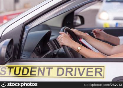 Middle-aged woman learning to drive a car with a driving instructor