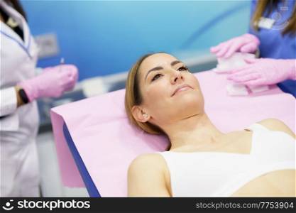 Middle-aged woman lying on the stretcher in an aesthetic clinic waiting for a botulinum toxin treatment.. Middle-aged woman lying on the stretcher in an aesthetic clinic.
