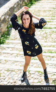 Middle-aged woman, model of fashion, wearing flowered dress in an old neighborhood of Granada in summer. Middle-aged woman wearing flowered dress in urban steps.