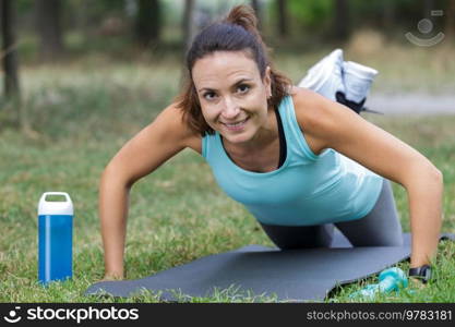 middle-aged woman performing side plank outdoors