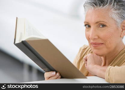 Middle-aged woman reading book on sofa
