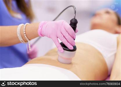 Middle-aged woman receiving anti-cellulite treatment with radiofrequency machine in a beauty center.. Woman receiving anti-cellulite treatment with radiofrequency machine in an aesthetic clinic.