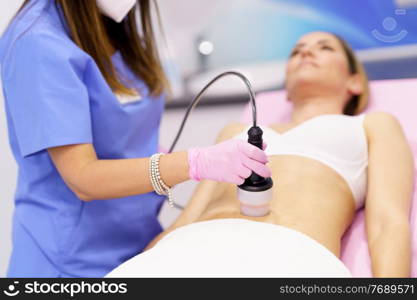 Middle-aged woman receiving anti-cellulite treatment with radiofrequency machine in an aesthetic clinic.. Woman receiving anti-cellulite treatment with radiofrequency machine in a beauty center.