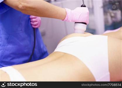 Middle-aged woman receiving anti-cellulite treatment with radiofrequency machine in an aesthetic clinic.. Woman receiving anti-cellulite treatment with radiofrequency machine in a beauty center.