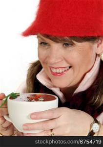 Middle aged woman rugged up for winter holding a hot cup of soup.