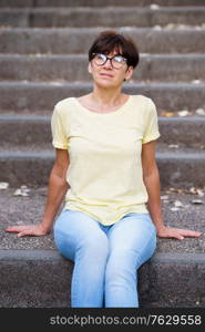 Middle-aged woman sit on the street on urban steps.. Beautiful Middle-aged woman sit on the street