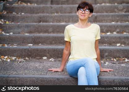 Middle-aged woman sit on the street on urban steps.. Beautiful Middle-aged woman sit on the street
