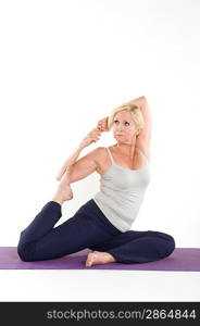 Middle aged woman stretching on yoga mat over white background