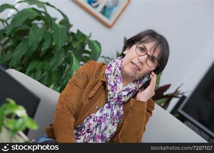 middle-aged woman talking on the phone at home