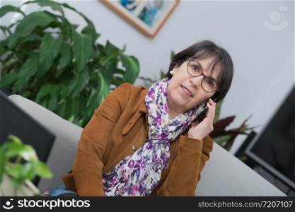 middle-aged woman talking on the phone at home