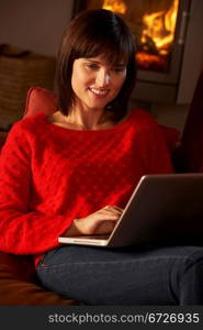 Middle Aged Woman Using Laptop Computer By Cosy Log Fire