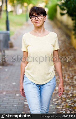 Middle-aged woman walking down the street in summer. Beautiful Middle-aged woman walking down the street