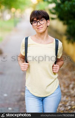 Middle-aged woman walking in a city park in summer. Beautiful Middle-aged woman walking down the street