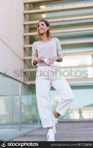 Middle aged woman wearing casual clothes carrying an eco-friendly ecological metal water bottle. Caucasian female in urban background.. Middle aged woman carrying an eco-friendly ecological metal water bottle.
