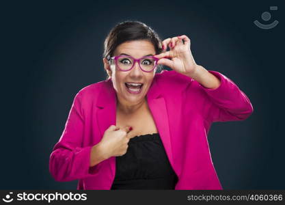 Middle aged woman with a happy face holding her own glasses and pointing to herself