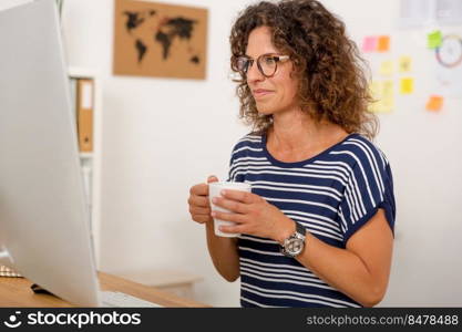 Middle aged woman working on the office and drinking coffee