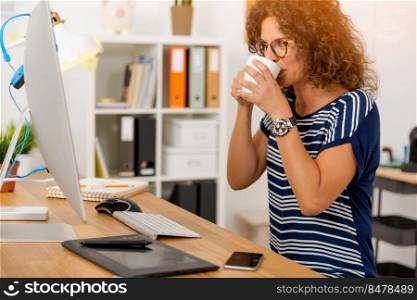 Middle aged woman working on the office and drinking coffee