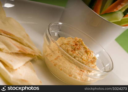 middle eastern hummus dip on a glass bowl with homemade pita bread and raw vegetable