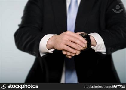 Middle section of a businessman watching his wrist watch.