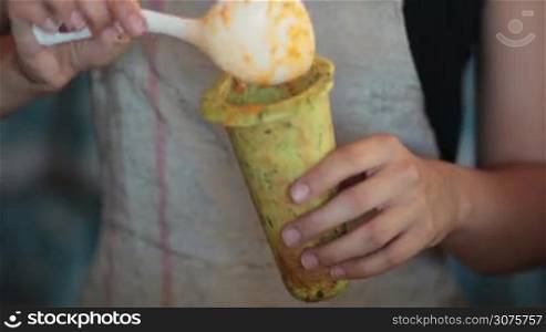 Middle section of woman pouring with spoon hot vegetable soup into baked cone