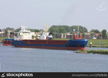 Middle size ship transporting containers over a canal