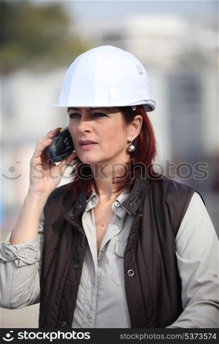 middleaged female architect making a call in construction site
