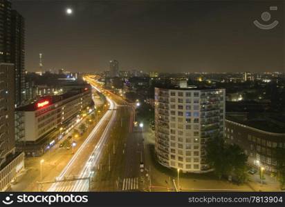 Midnight traffic in Rotterdam, the Netherlands, seen from above. The moon and the Euromast are in view, the suburbs and residential areas on the right