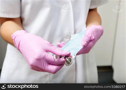Midsection of a female dentist holding plaque remover and angled mirror. Dentist holding plaque remover and angled mirror