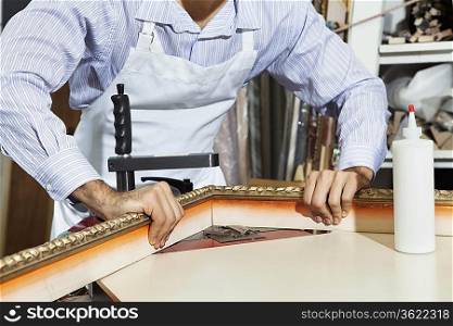 Midsection of a young craftsman working on picture frame&acute;s corner