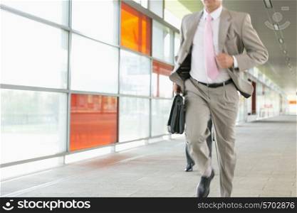 Midsection of businessmen rushing on railroad platform