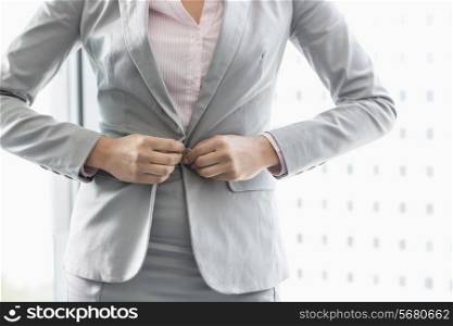 Midsection of businesswoman buttoning her blazer