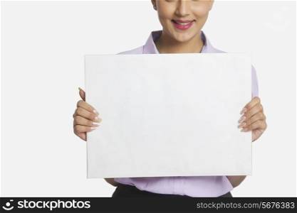 Midsection of businesswoman holding empty placard over white background